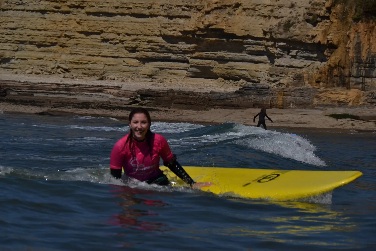 Smiling surfer walking out of the water below the cliffs